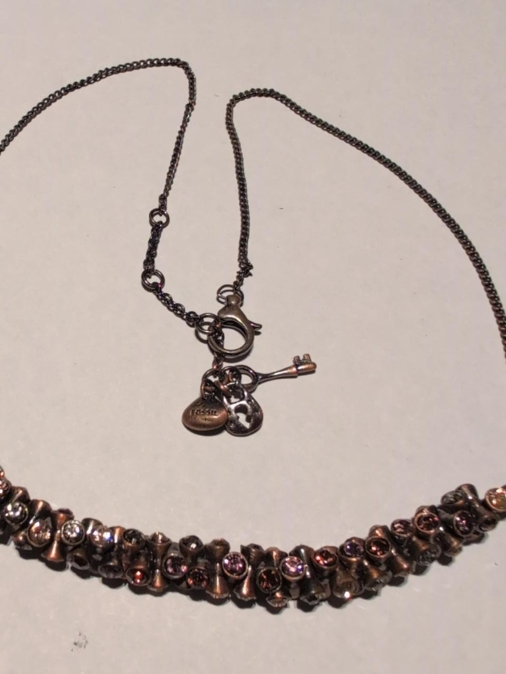 Fossil gold and multi rhinestone necklace necklace with heart and key charms.